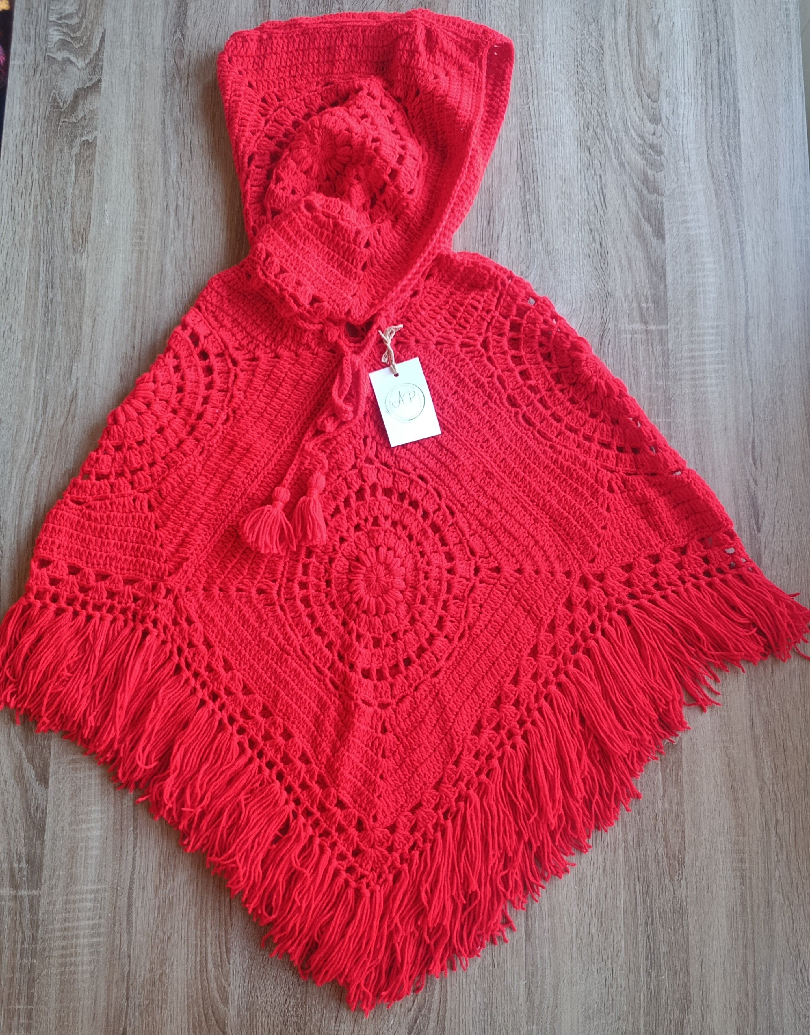 Poncho de crochê com capuz vermelho da Kukini Co., mostrando detalhes do tecido e design aconchegante.