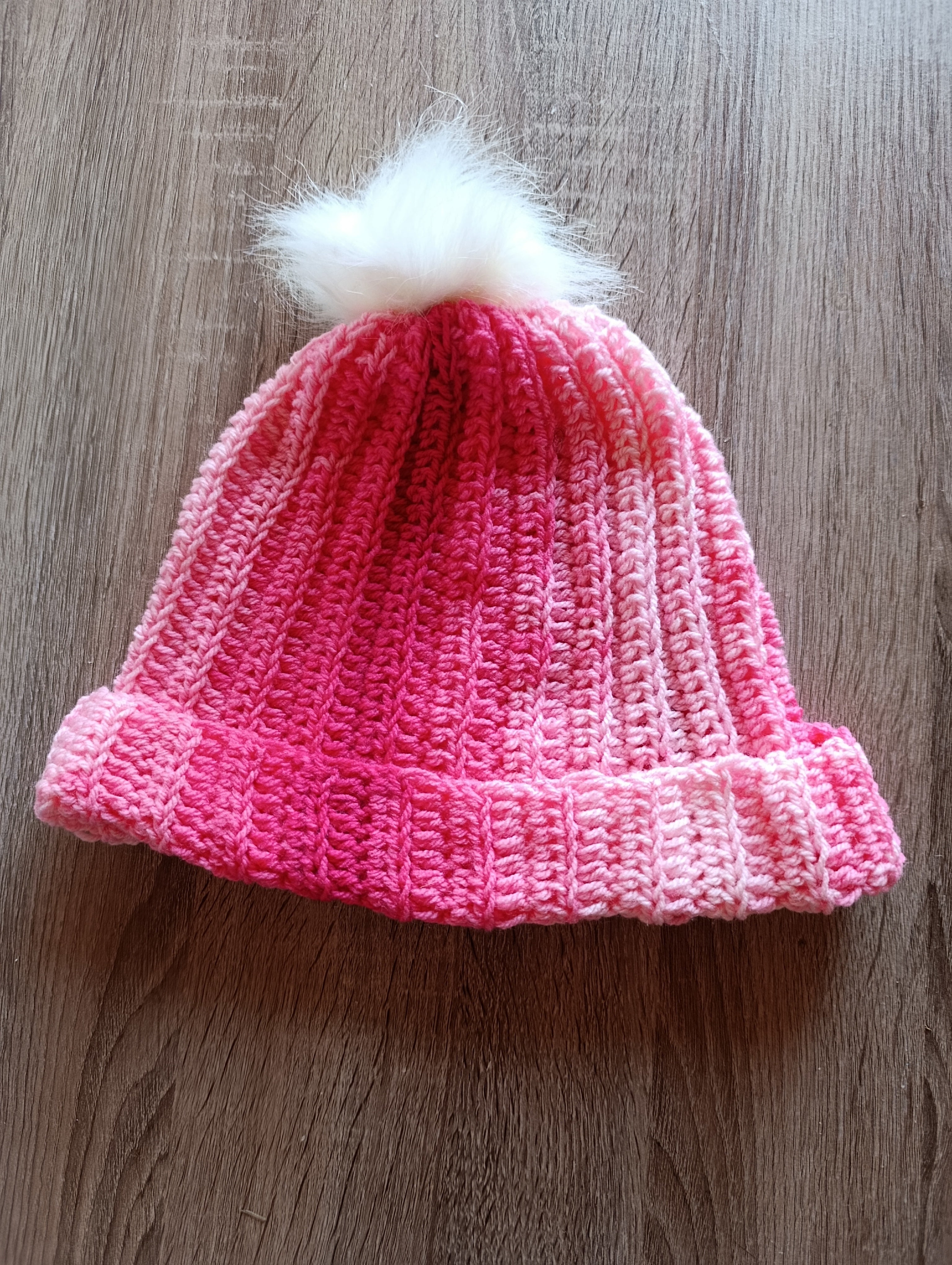 Gorro de crochê rosa com pompom da Kukini co., mostrando o detalhe do tecido e o pompom na parte superior.
