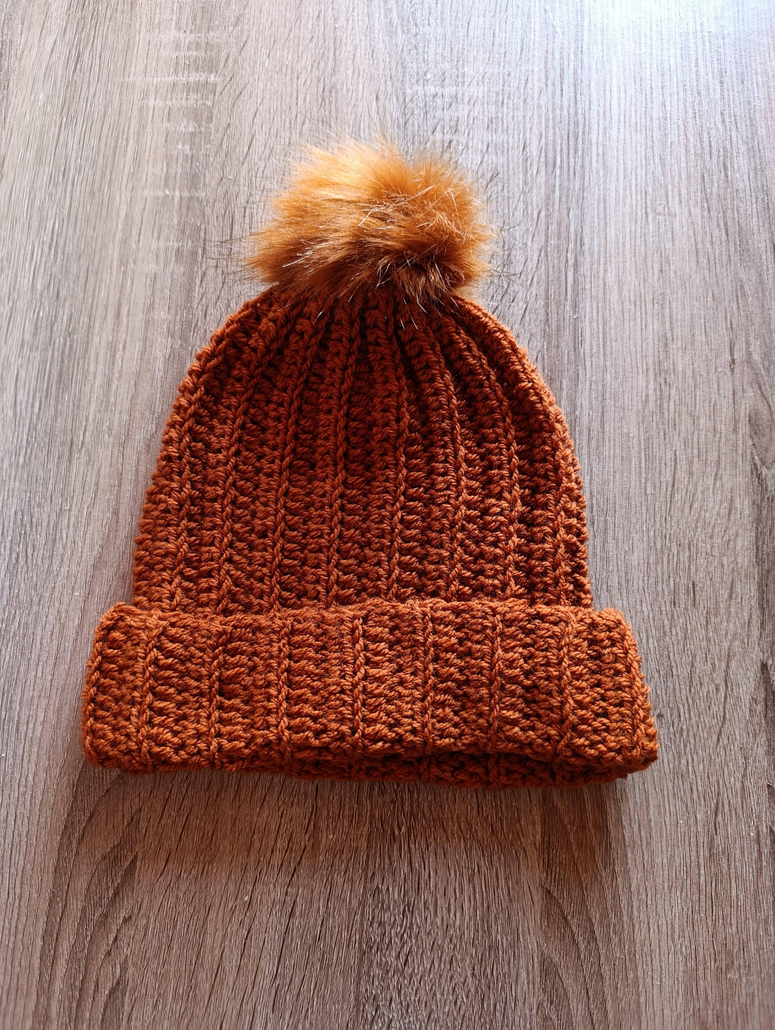Gorro de crochê terracota com pompom da Kukini Co., mostrando textura macia e detalhes do acabamento.