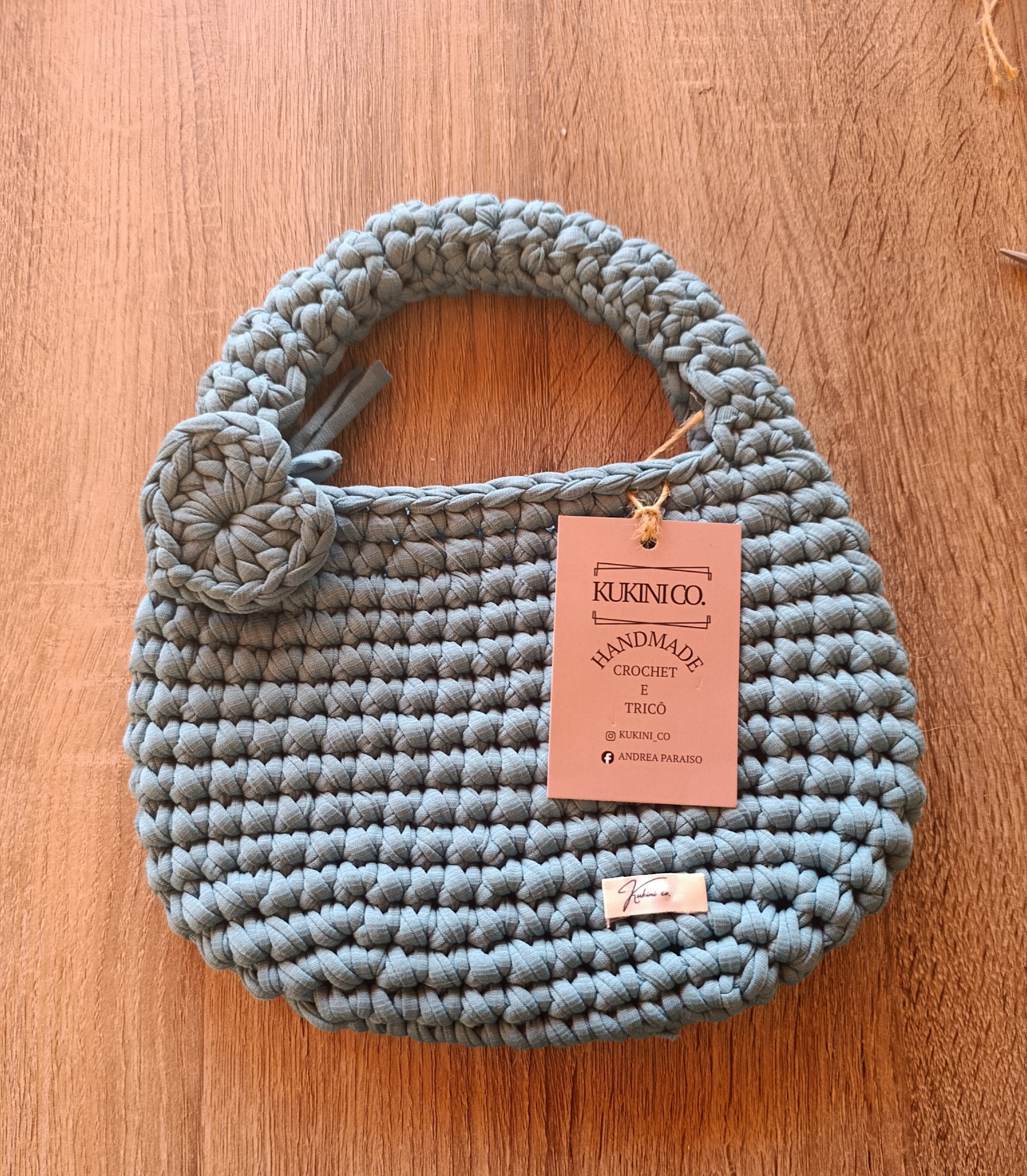 Mini tote bag de crochê azul acinzentado da Kukini Co., bolsa pequena com alça resistente e acabamento detalhado.