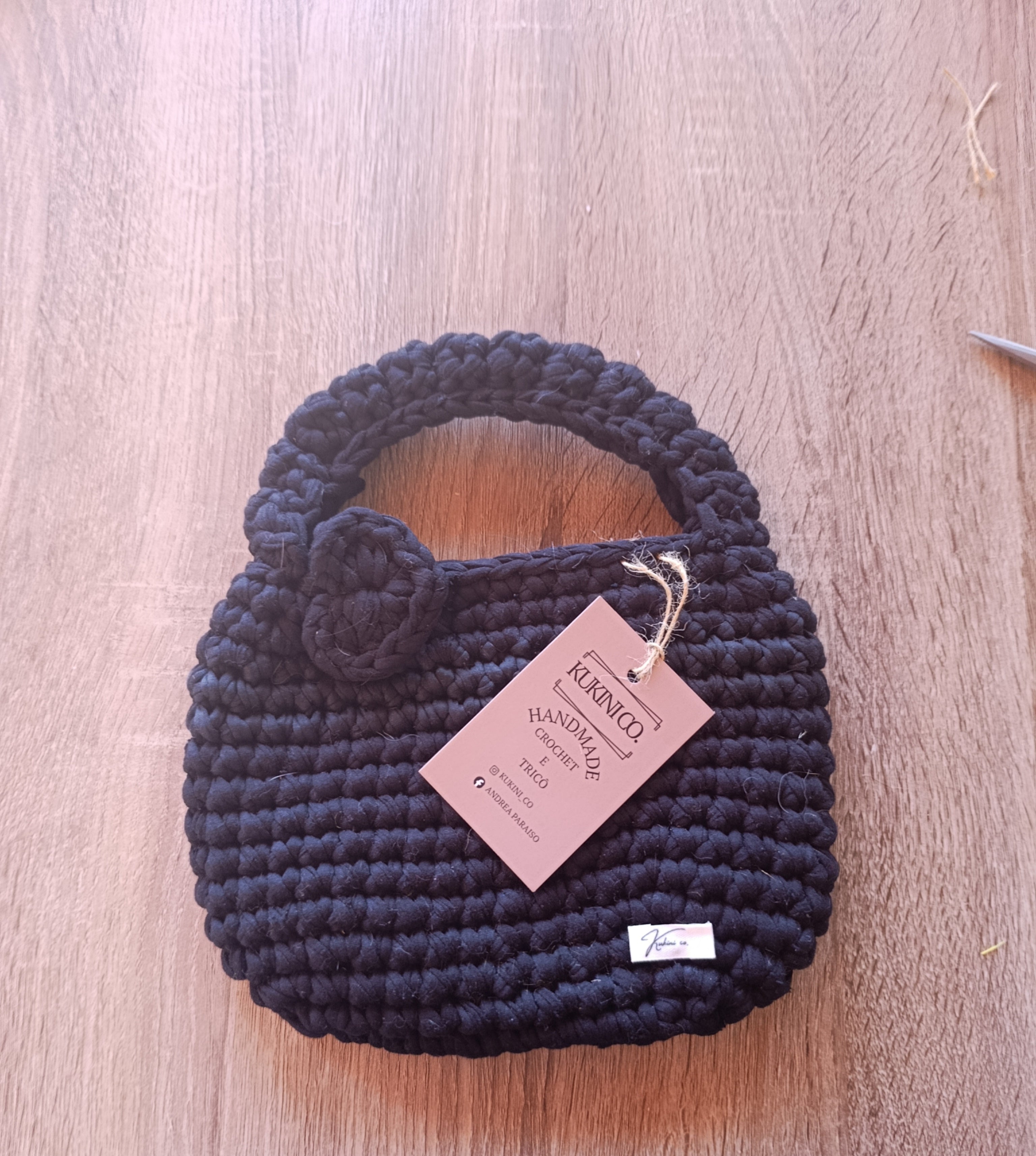 Bolsa tote mini de crochê preta da Kukini co., com alça curta e acabamento detalhado, ideal para uso casual.