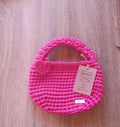 Mini tote bag de crochê rosa fúcsia da Kukini co., vista frontal mostrando alça e detalhes do tecido artesanal.
