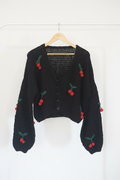 Casaco de crochet preto com detalhes de cerejas, estilo casual, sobre fundo branco, produzido pela Kukini Co.