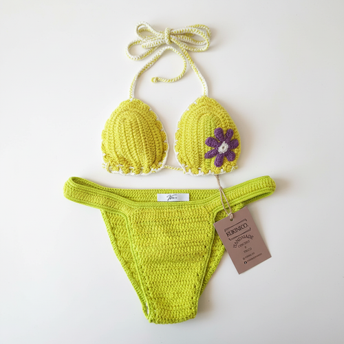 Biquíni crochet amarelo e verde com flor lilás da Kukini Co., mostrando detalhes do top e calcinha em tecido trançado.