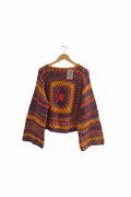 Suéter de tricô granny square roxo e laranja da Kukini Co., detalhe de pontos de crochê coloridos e padrão quadrado.