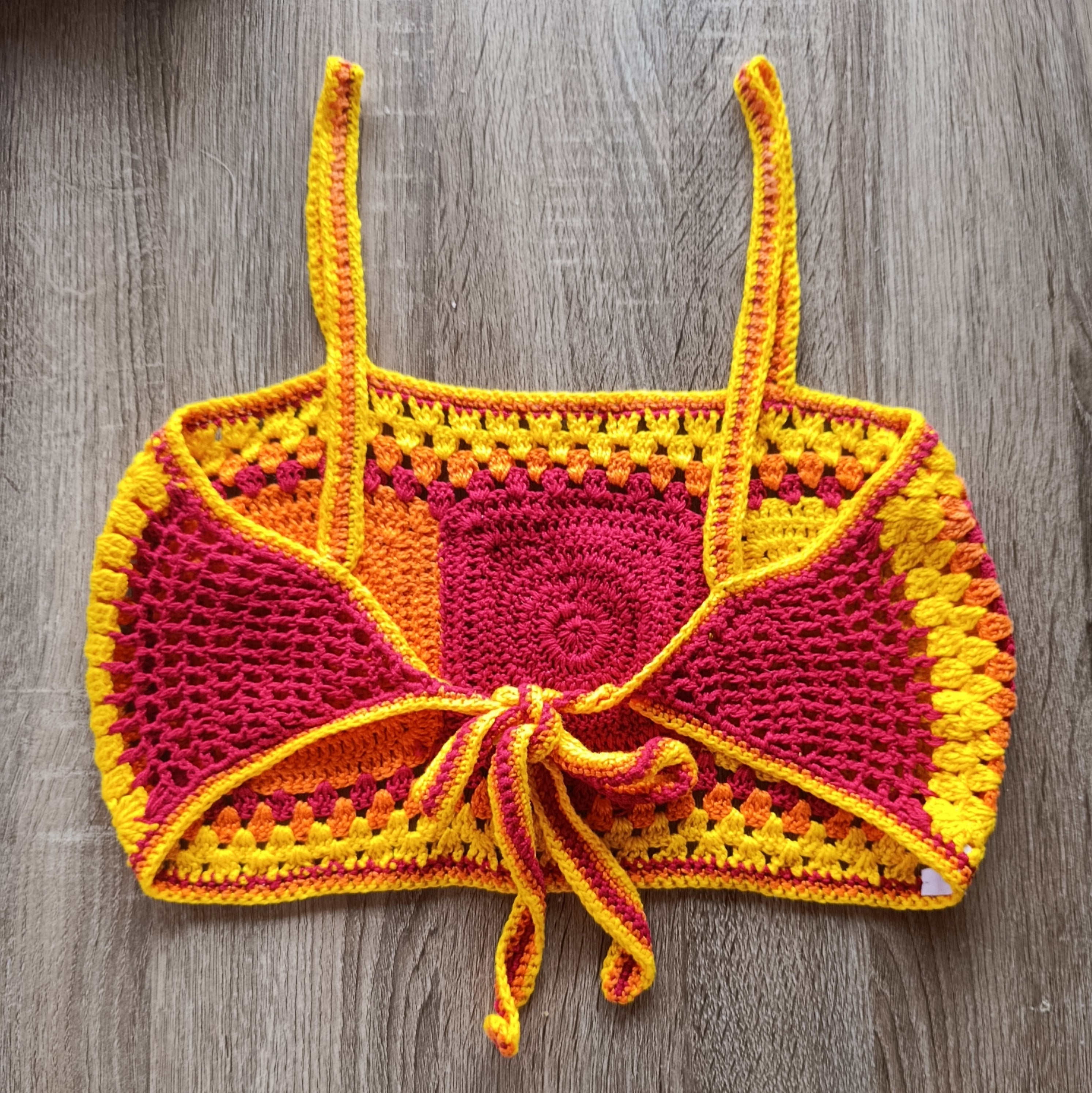 Top crochet curto feito à mão da Kukini Co., detalhe da textura e cores vibrantes do tecido artesanal.